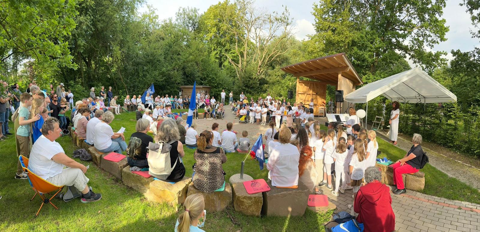 Menschen sitzen im Schöpfungsgarten